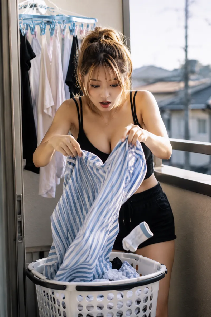 女性が、洗濯籠から衣類を取り出そうとして、衣類の中から突然靴下の片方が落下して驚いている決定的瞬間のAI写真｜GPT Image 2.0