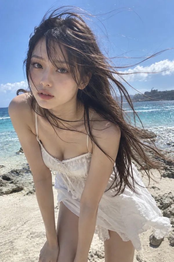 真夏のビーチ。強い日差しと海風、青い海を背景にした日本人女性の写真。