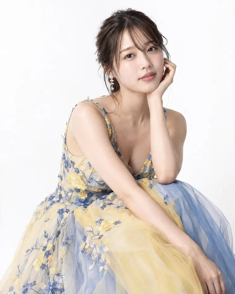 中判カメラによるスタジオ写真風。黄色と青色のアクセントがあるドレス姿の20歳の日本人女性が白いバックペーパーの前にいる。