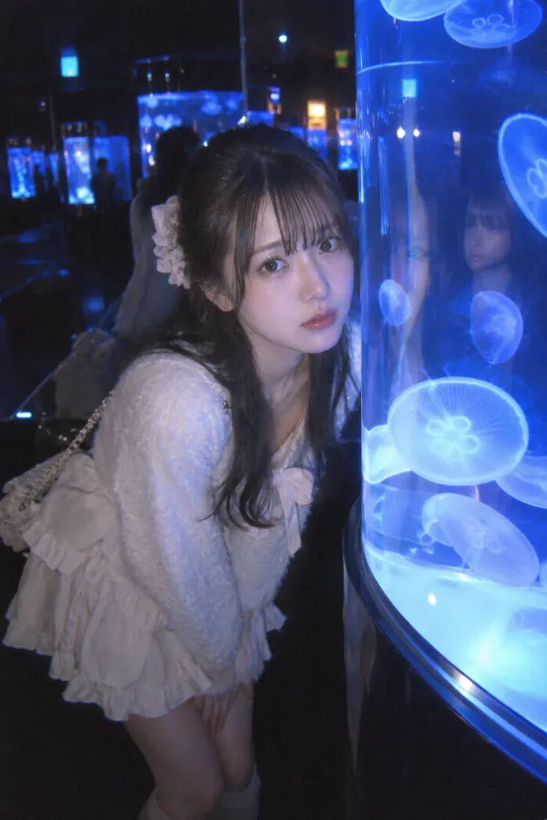 水族館のクラゲ展示。青い光と水槽の反射が広がる幻想的な実写写真。