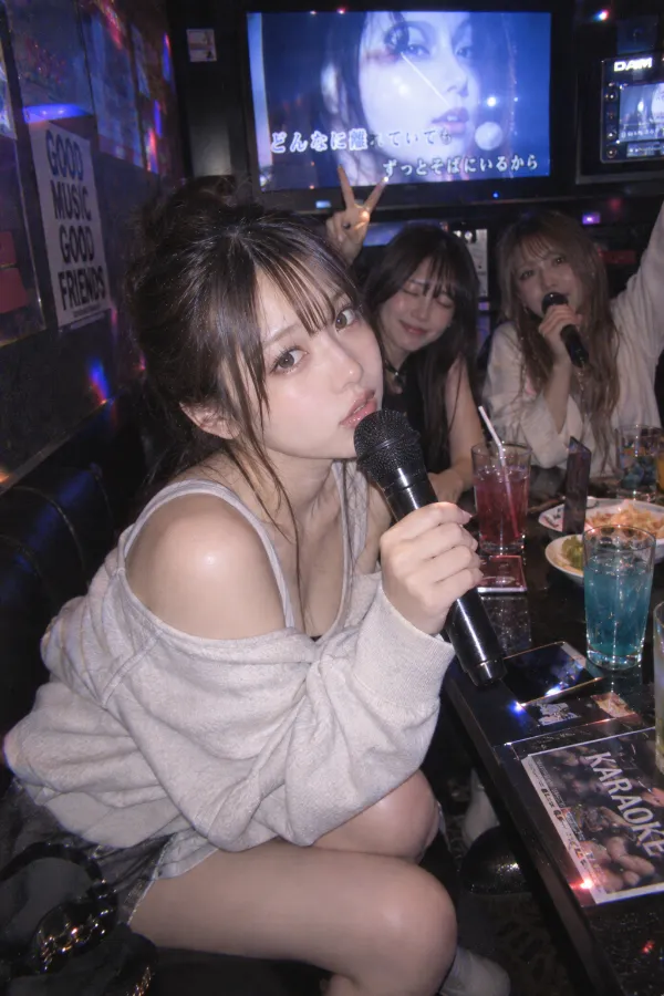 夜のカラオケルーム。大画面、マイク、ドリンクと友人たちが写る実写写真。
