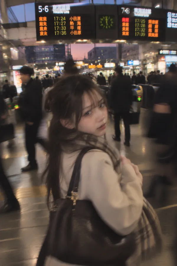 夕方の駅コンコース。改札、電光掲示板、帰宅客で混雑する実写写真。