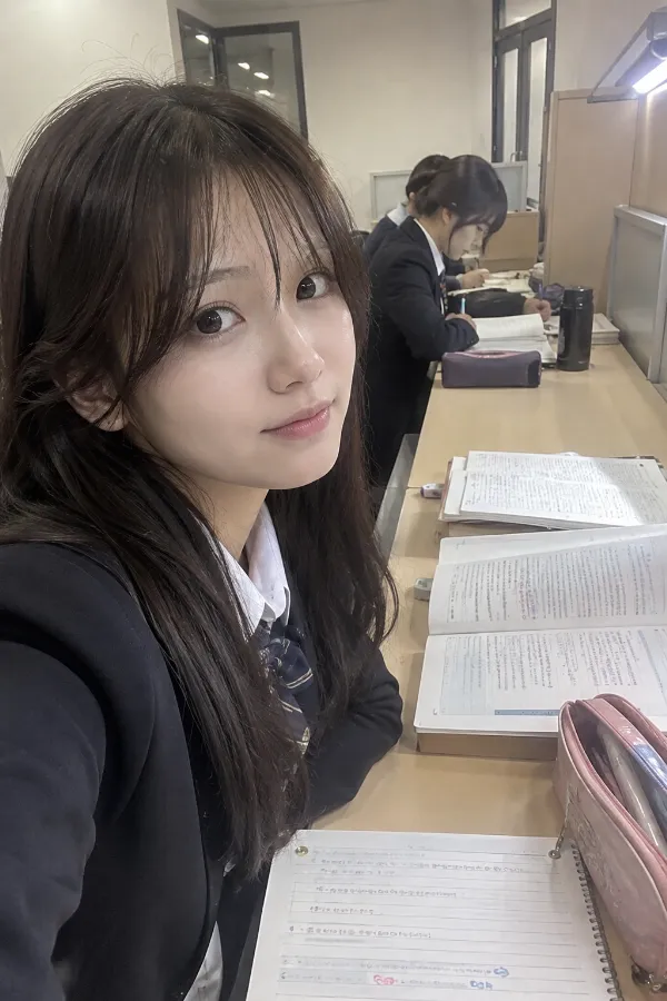 自習室の机。参考書、ノート、筆箱を広げて勉強する学生がいる実写プロンプト作例。