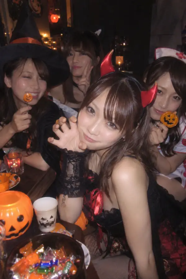 ハロウィンパーティー。かぼちゃやお菓子、仮装した友人たちが集まる室内風景。